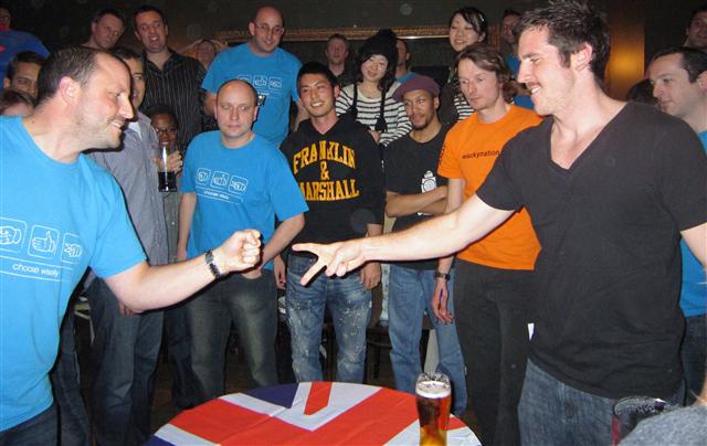 Competitors at the 4th UK Rock Paper Scissors Championships in 2010.  The game ‘rock paper scissors’ uses six words; three objects (nouns) and three actions (verbs), and is played without speaking.  Each player presents the other with an ‘object’, represented as a gesture.  The way these objects interact is already understood by the participants.  As they play, the phrases, i.e. the ‘unspoken rules’ of the game, come to mind (Image: Wikimedia Commons)