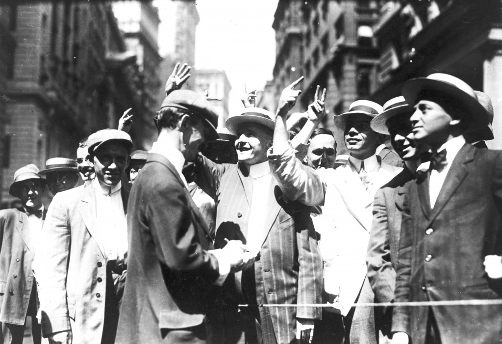This photograph of the New York Curb Association market (c1916) shows brokers and clients signalling from street to offices using stylised gestures.  Similar manual signs have arisen in many open floor stock exchanges around the world, where they made it possible to broker rapid ‘face-to-face’ deals across a noisy room (known as the ‘open outcry’ method of trading).  Today these manual languages have been largely superseded by the advent of telephones and electronic trading through the 1980’s and 1990’s (Image: Wikimedia Commons)