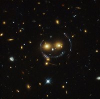 إن سبب "الوجه" و "الإبتسامة" في هذه الصورة لكتلة المجرة SDSS J1038 + 4849 هو ظاهرة عدسة الجاذبية gravitational lensing  (الصورة: NASA / ESA)